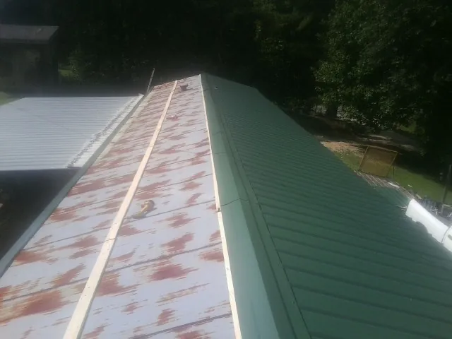 Old rusted panels beside newly installed green metal roofing — Wind Damage Roof Repair by Roofing Brothers in Shelton
